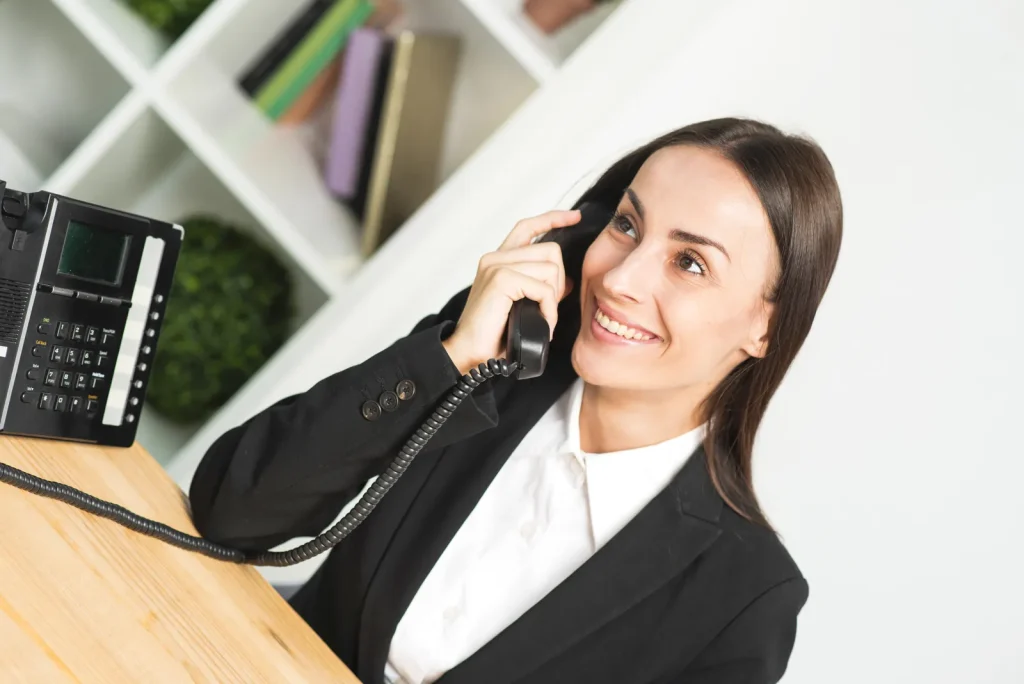 Giovane impiegata sorridente al telefono in un ufficio