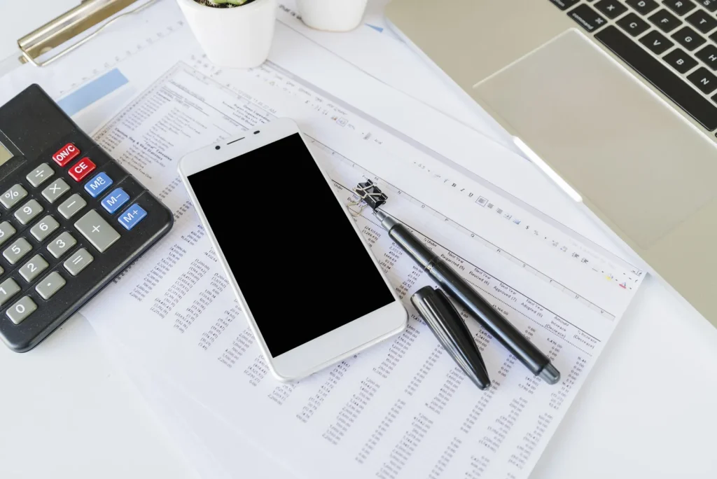 Scrivania con calcolatrice, smartphone e un foglio di dati stampato